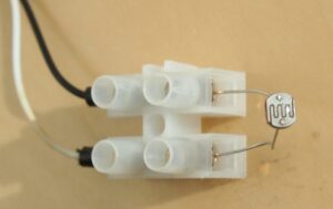 Ein lichtempfindlicher Widerstand, mit einer Lüsterklemme mit einem schwarzen und einem weissen Kabel verbunden.